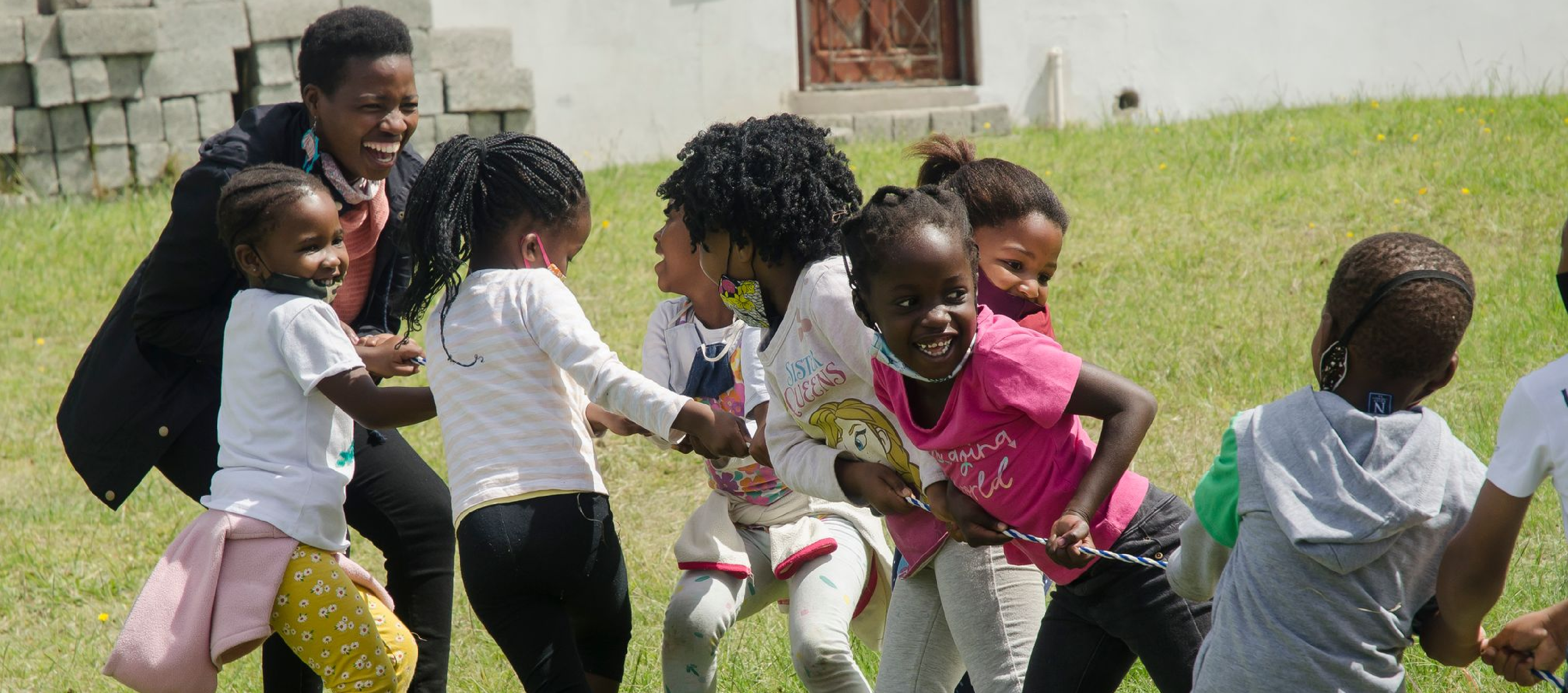 African children and teachers playing tug-o-war in the sunshine as part of teacher training and early childhood development